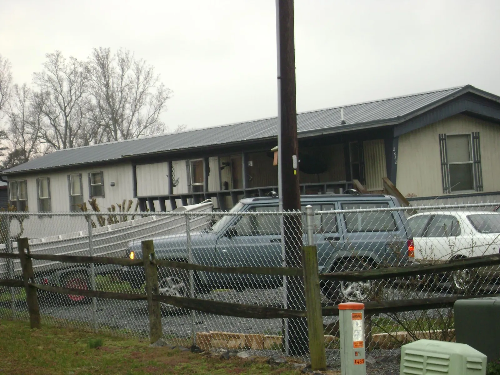 Dark metal roof on a long single story building behind a chain link fence in West Rutland