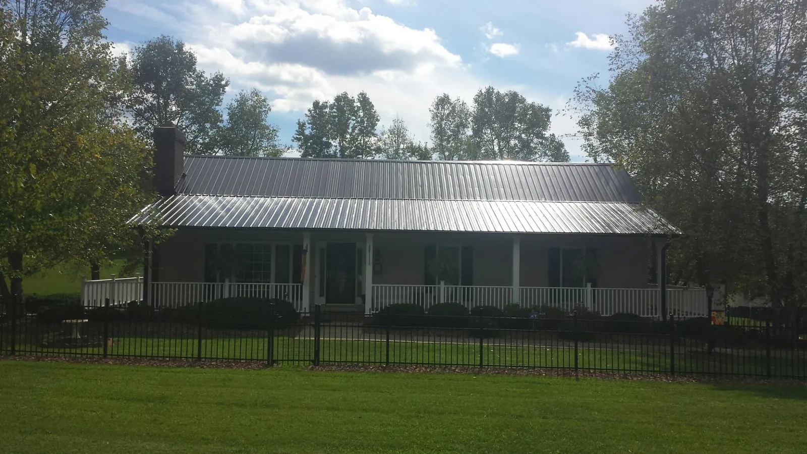 Gray metal roof on a brick ranch with a full width front porch — Gutter Guard Installation work by our crew in West Rutland