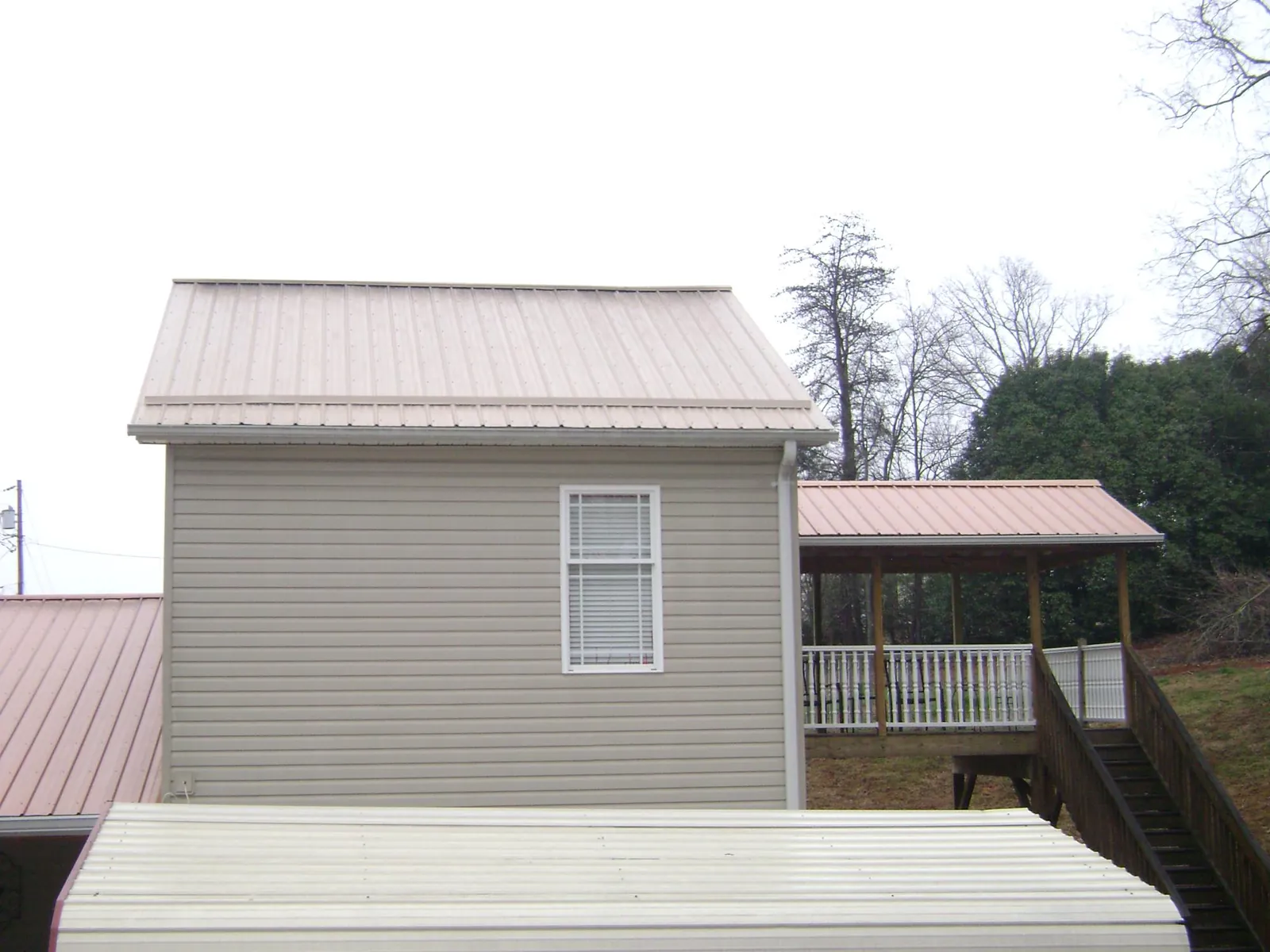 Tan metal roofs on a two story addition and attached porch, from a Roof Replacement job in West Rutland