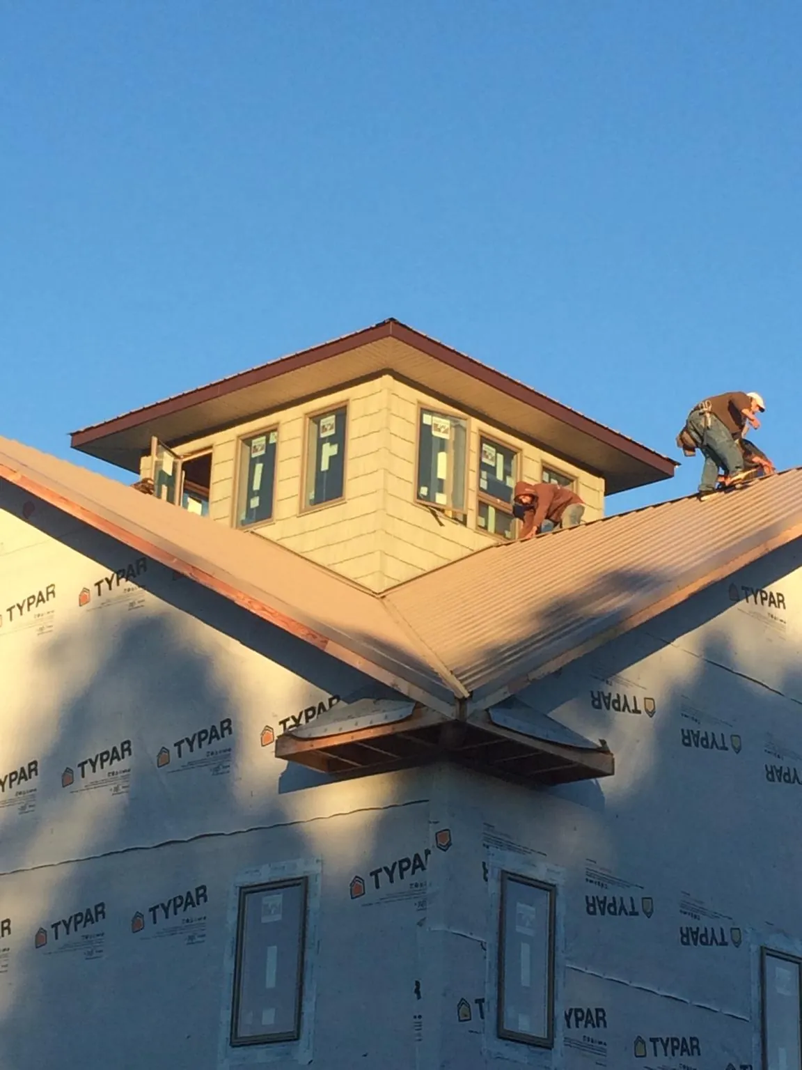Roofers working around a rooftop cupola on a new metal roof at sunset — Roof Waterproofing in West Rutland by Roofing Brothers